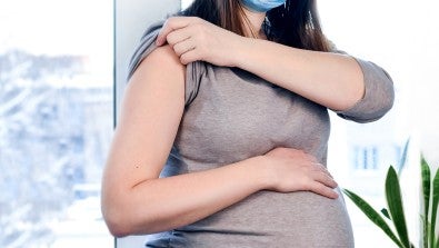 pregnant woman with her arm exposed for a vaccine shot