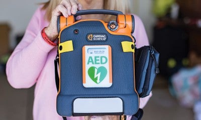 An AED is an automated external defibrillator, a small compact device that can help save someone’s life during sudden cardiac arrest. 