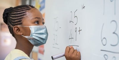 child in mask at dry erase board