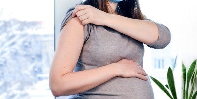pregnant woman with her arm exposed for a vaccine shot