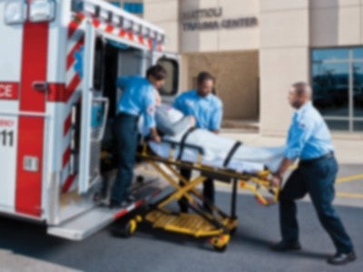 Emergency responders wheeling a patient into an ambulance